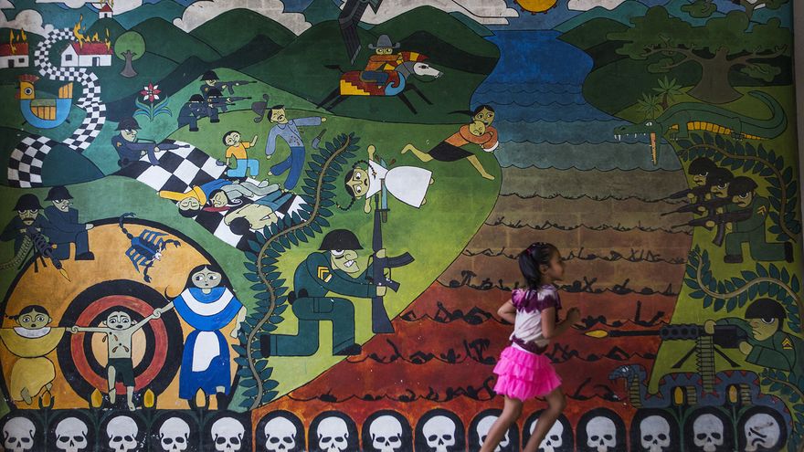 Una niña camina junto a uno de los murales que recuerdan el conflicto armado interno de El Salvador en Carasque (Foto: Oliver de Ros)